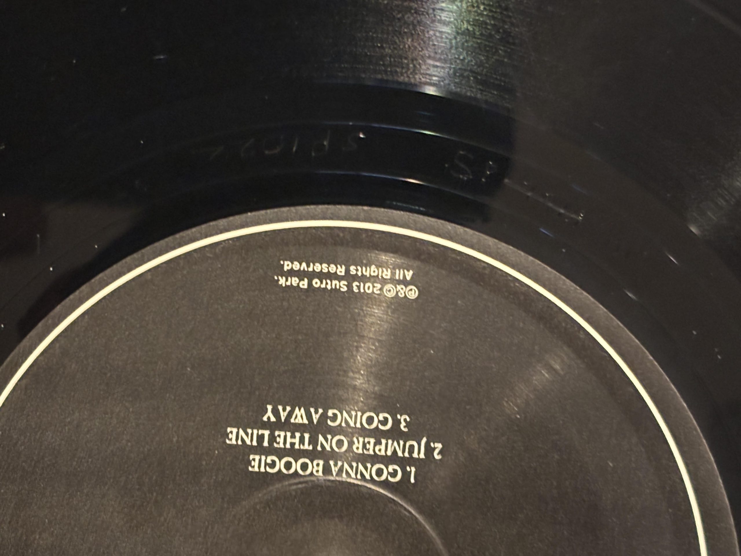 Close-up of vinyl record deadwax showing etched matrix numbers, stamps, and record label details