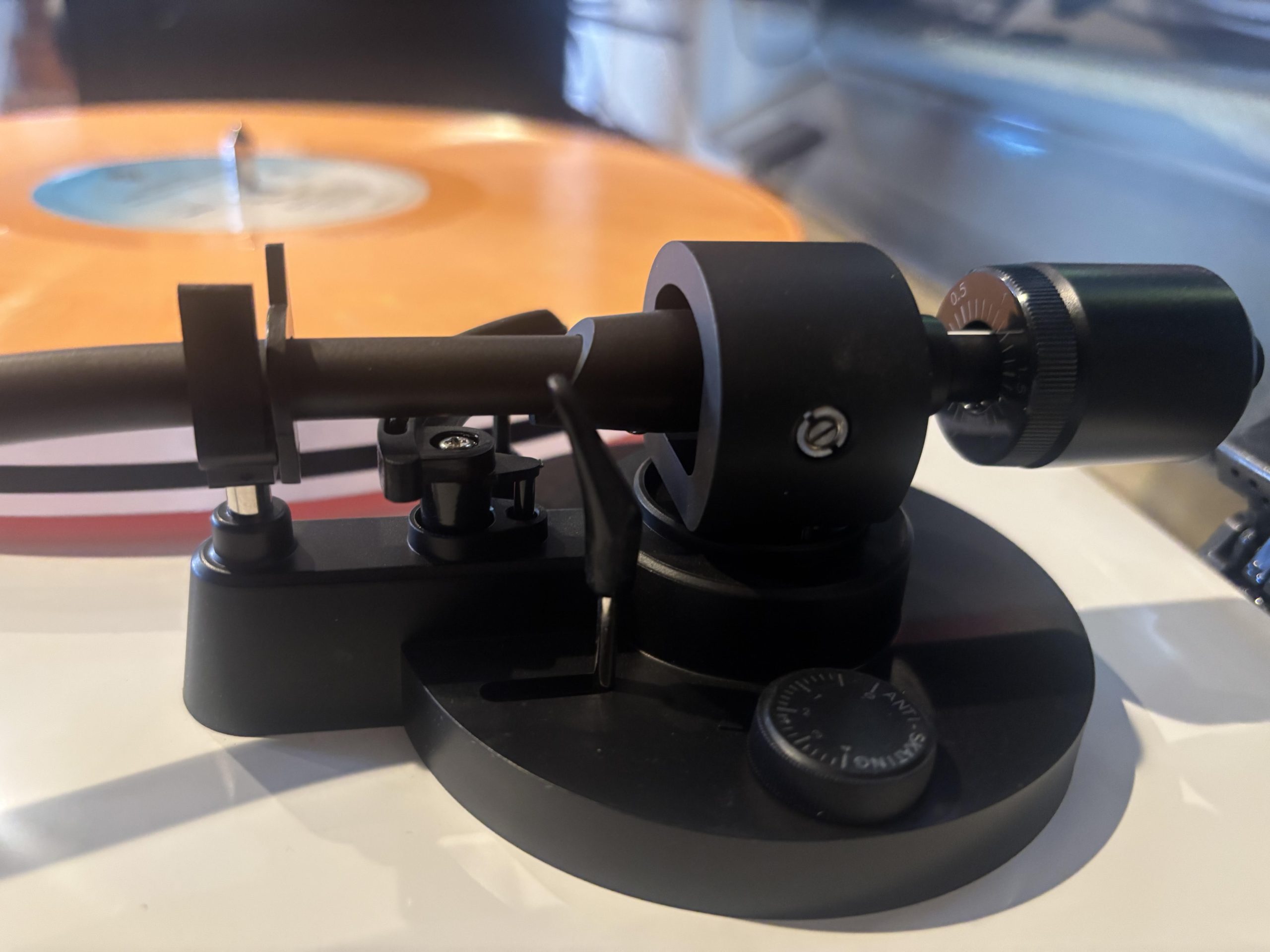 Adjusting the counterweight on a turntable tonearm to set proper tracking force for vinyl playback.